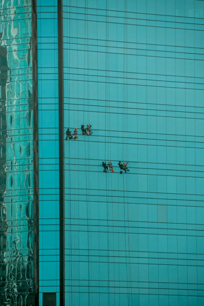 High-rise window cleaners working on a glass skyscraper with stunning reflections.